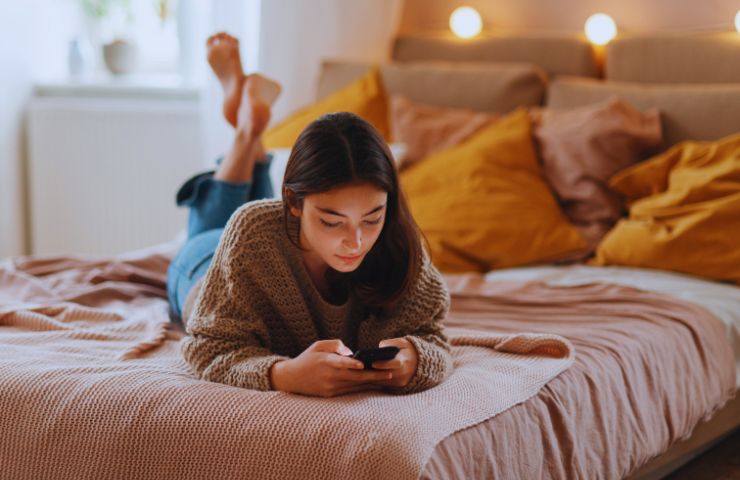 ragazza con smartphone sul letto